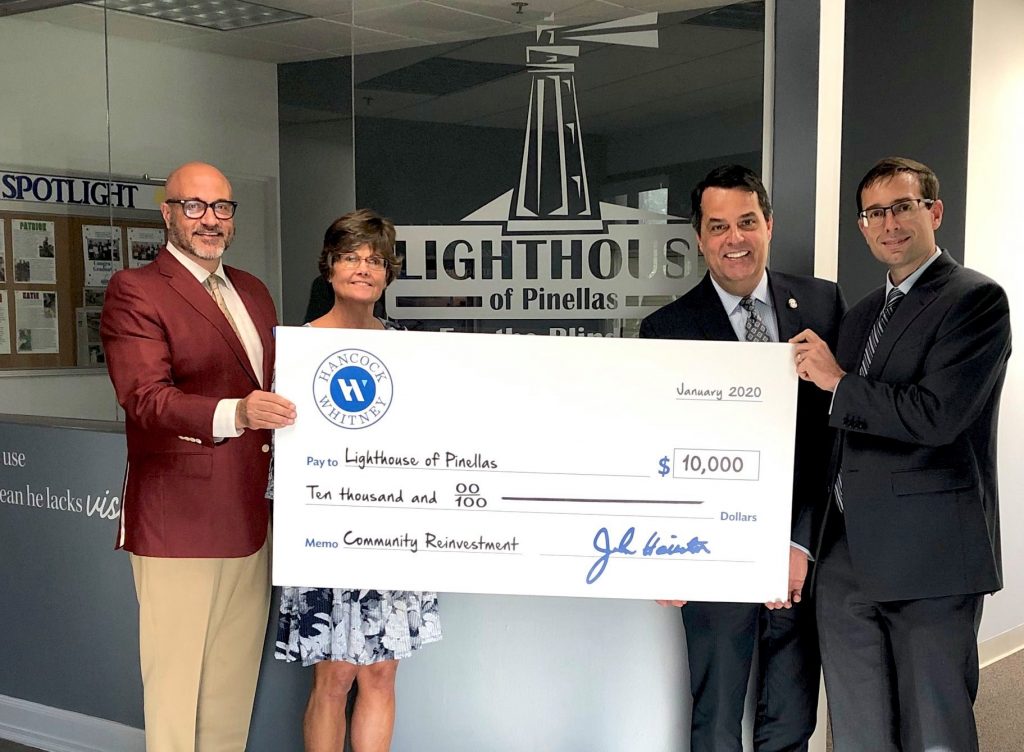 Representatives from Hancock Whitney holding large donation check with Lighthouse Pinellas CEO, Kim Church