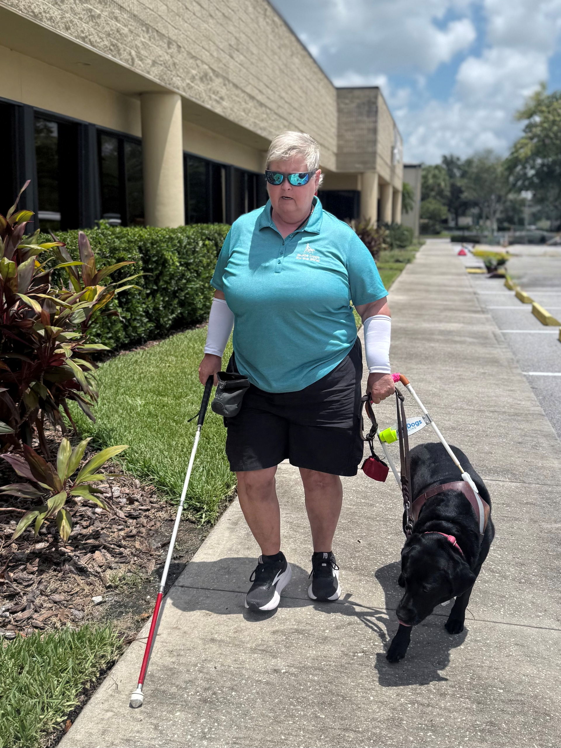 2025 Impact Report Kandie and her seeing eye dog, Runner, outside the Lighthouse office building.